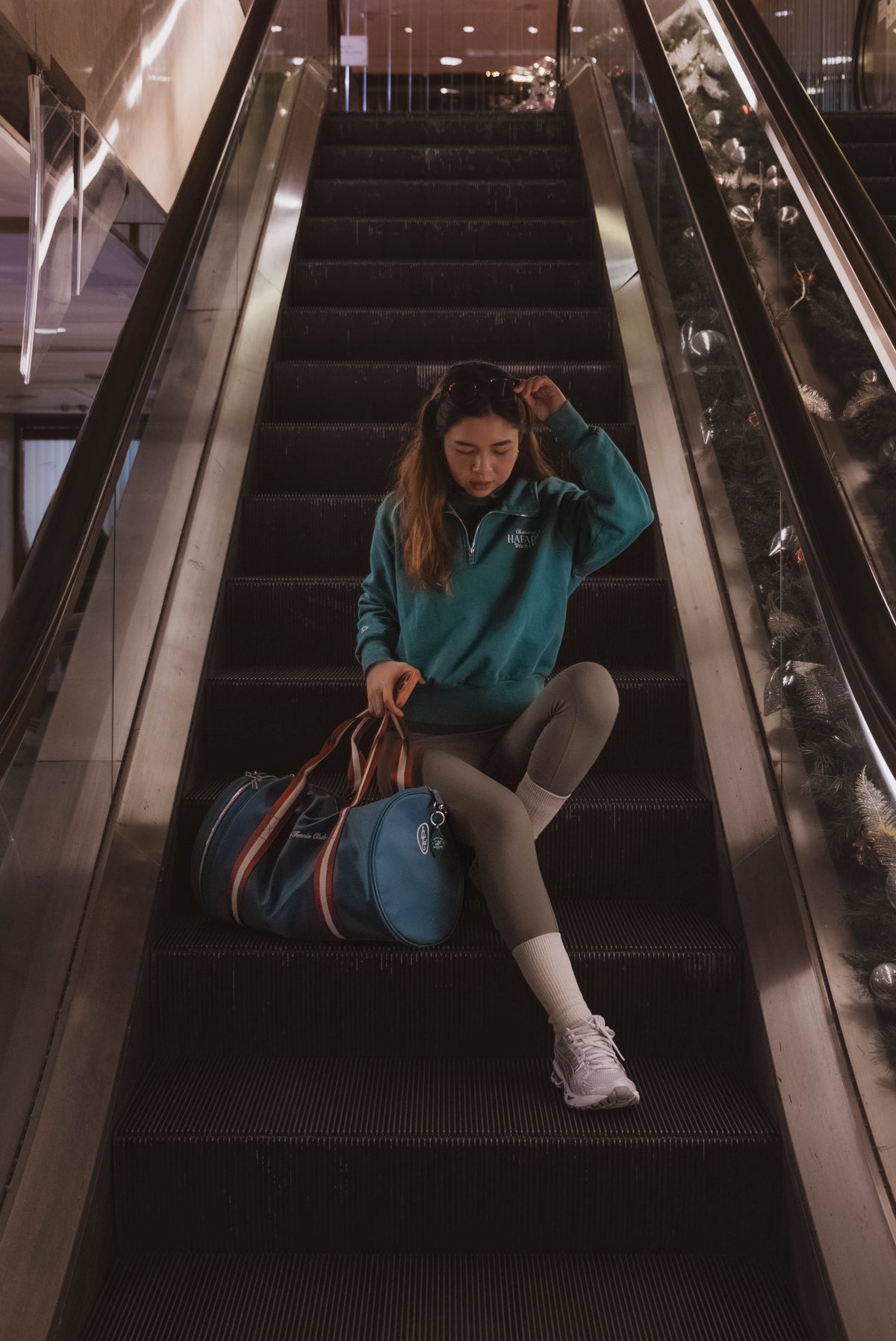 Person sitting on an escalator with a blue bag